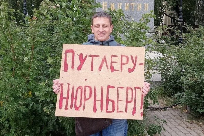 <em>Григорий Северин в одиночном пикете. За этот же плакат в январе 2021 года его <a href="https://axmwjdvv---mekodxpr-bsccljbcrq-ez.a.run.app/express-news/2021/01/20/voronezhca-arestovali-iz-za-odinochnogo-piketa-v-podderzhku-navalnogo"><u>арестовали</u></a> на пять суток (ч. 8 ст. 20.2 КоАП РФ) / Фото: Свободные Люди Воронежа</em>